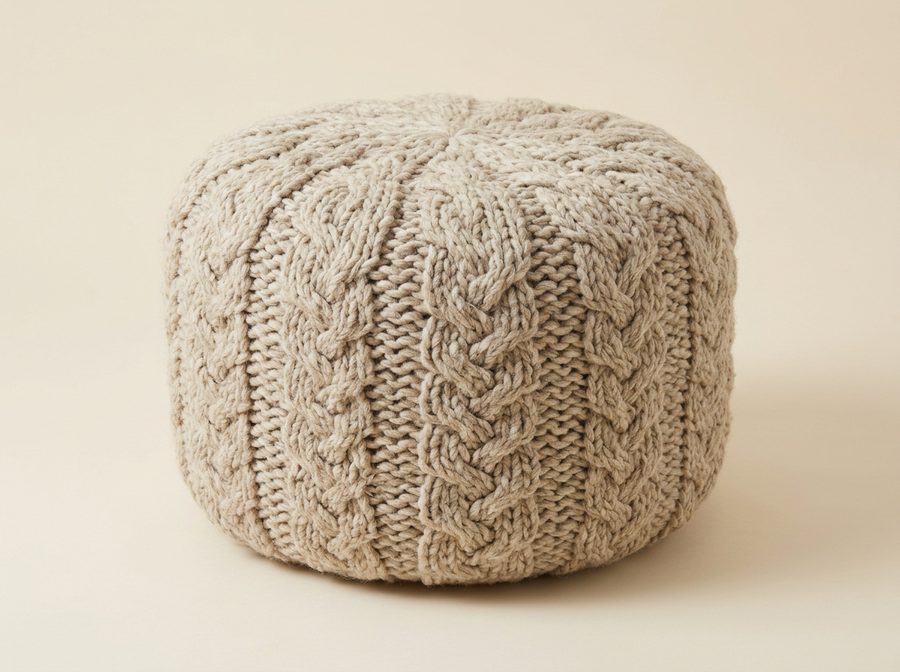Pouf rond en grosse maille de laine écrue torsadée, posé au sol